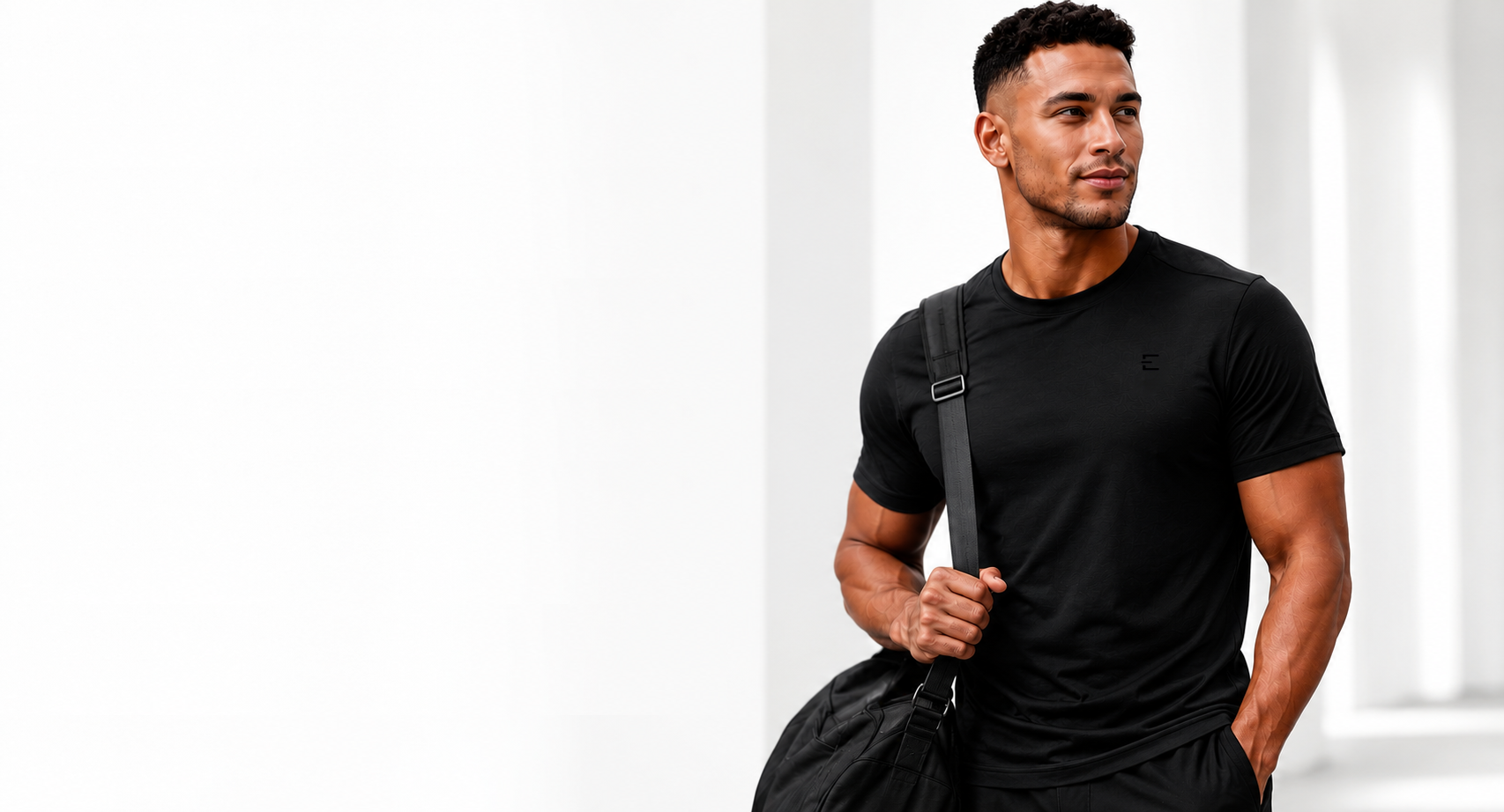 Man wearing ENFORCE black bamboo performance tee with duffel bag
